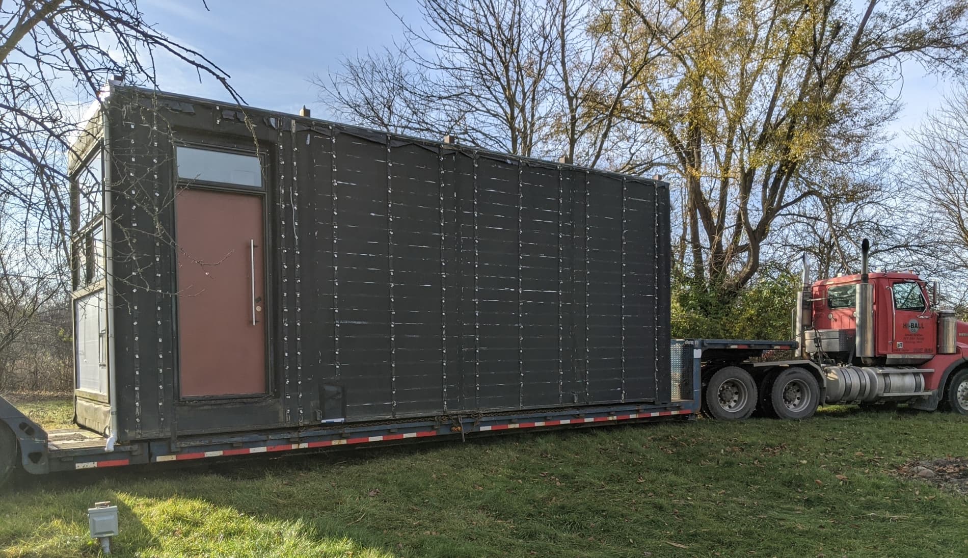 Tiny home on the lowboy trailer being towed away by the semi